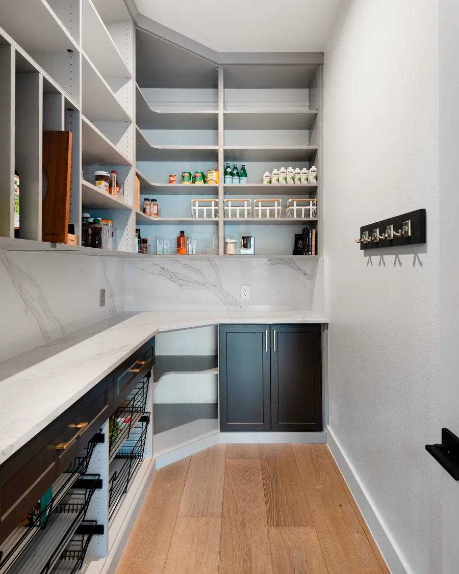 Walk-in pantry with open shelving, dark base cabinets and a marble counter
