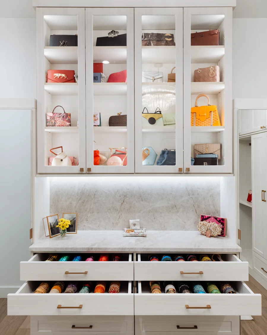 Lit closet shelving above a marble counter with open shoe drawers below