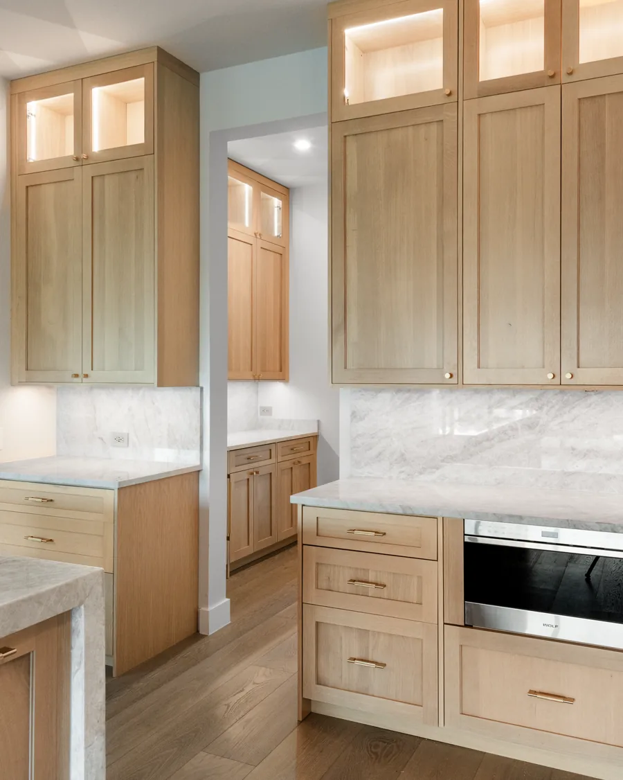Custom white oak kitchen cabinets with tall upper cabinets and marble counters