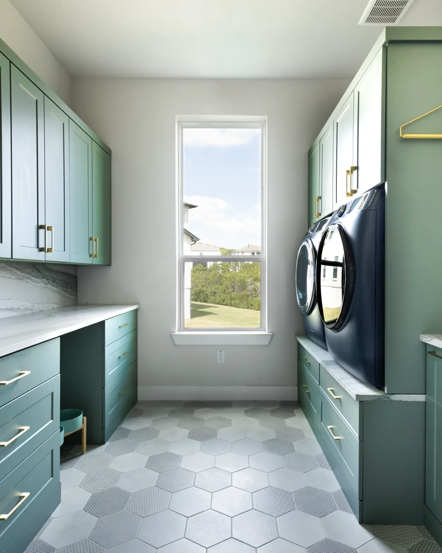 Laundry room with green cabinetry, a folding counter and a window between runs