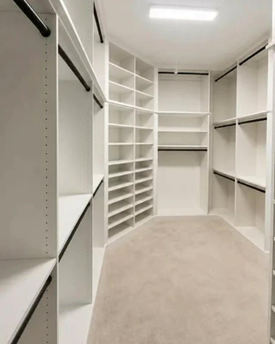 Walk-in closet with full-height shoe shelving down one wall and hanging on both sides
