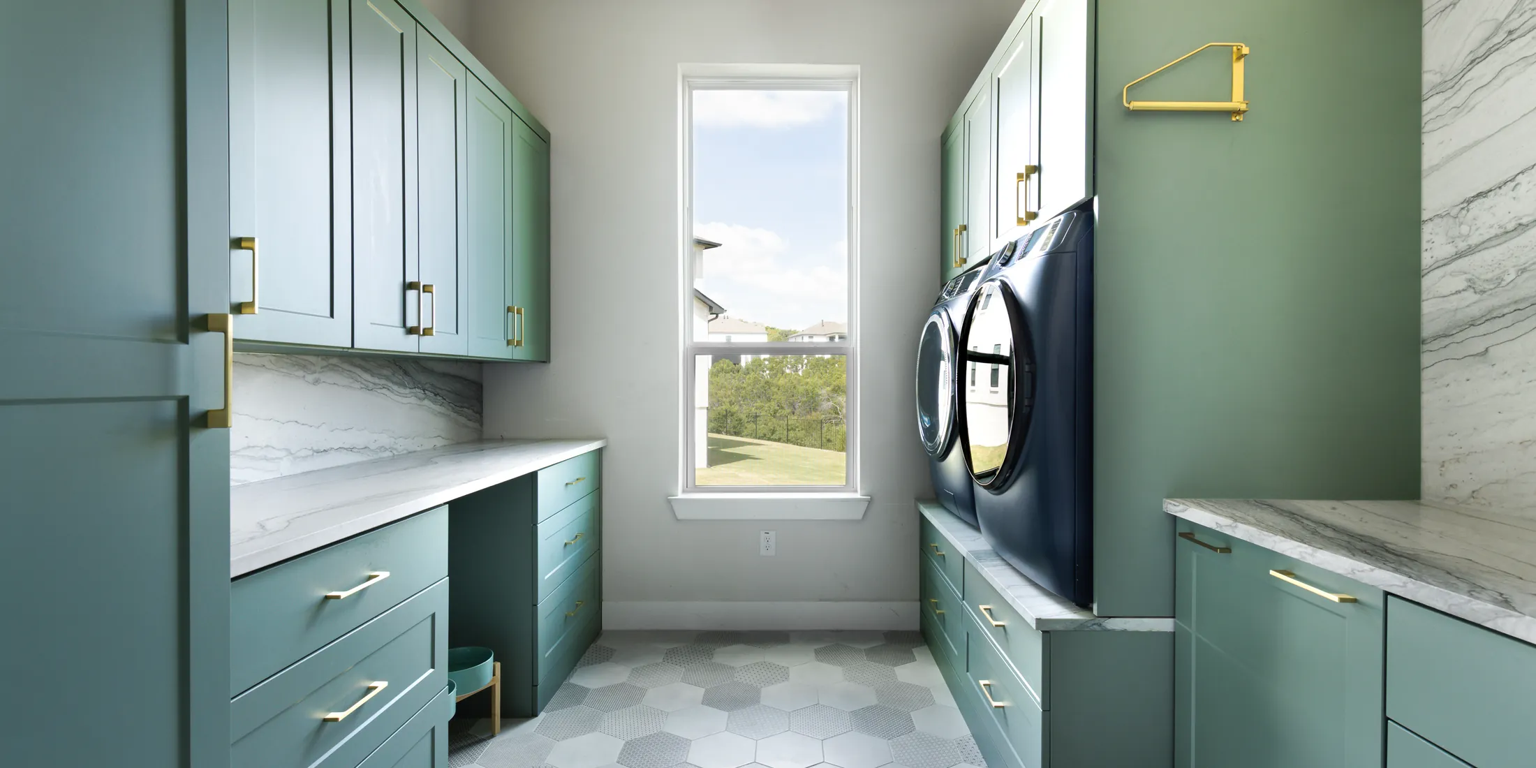 Sage green laundry room cabinets with a marble counter and a hex tile floor
