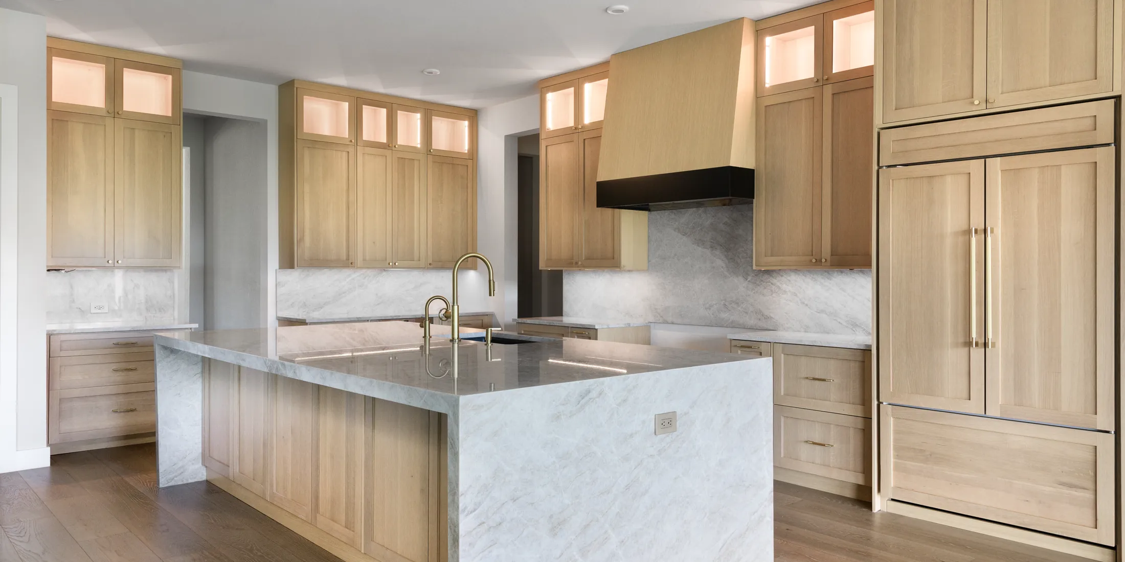 White oak kitchen cabinets around a marble waterfall island in an Austin home